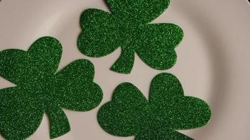 roterend voorraadbeeldschot van st Patty's dagklavers op een witte oppervlakte - st pattys 001 video