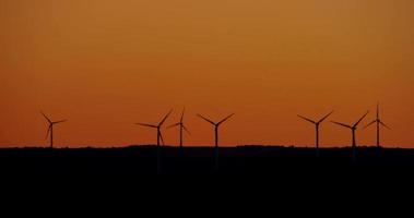 Wind farm in rural zone with seven eolic generators and a beautiful sunset in background in 4K