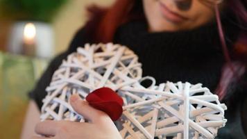 Valentine Gift. Young Girl holding white wooden heart with rose petals video