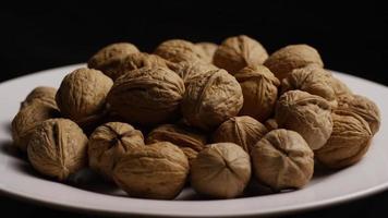 Cinematic, rotating shot of walnuts in their shells on a white surface - WALNUTS 081 video