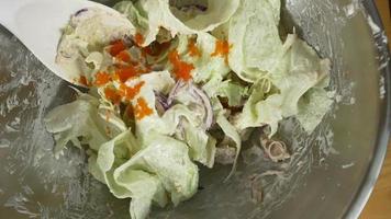 vista de cima do jovem chef jogando uma saborosa salada verde orgânica. video