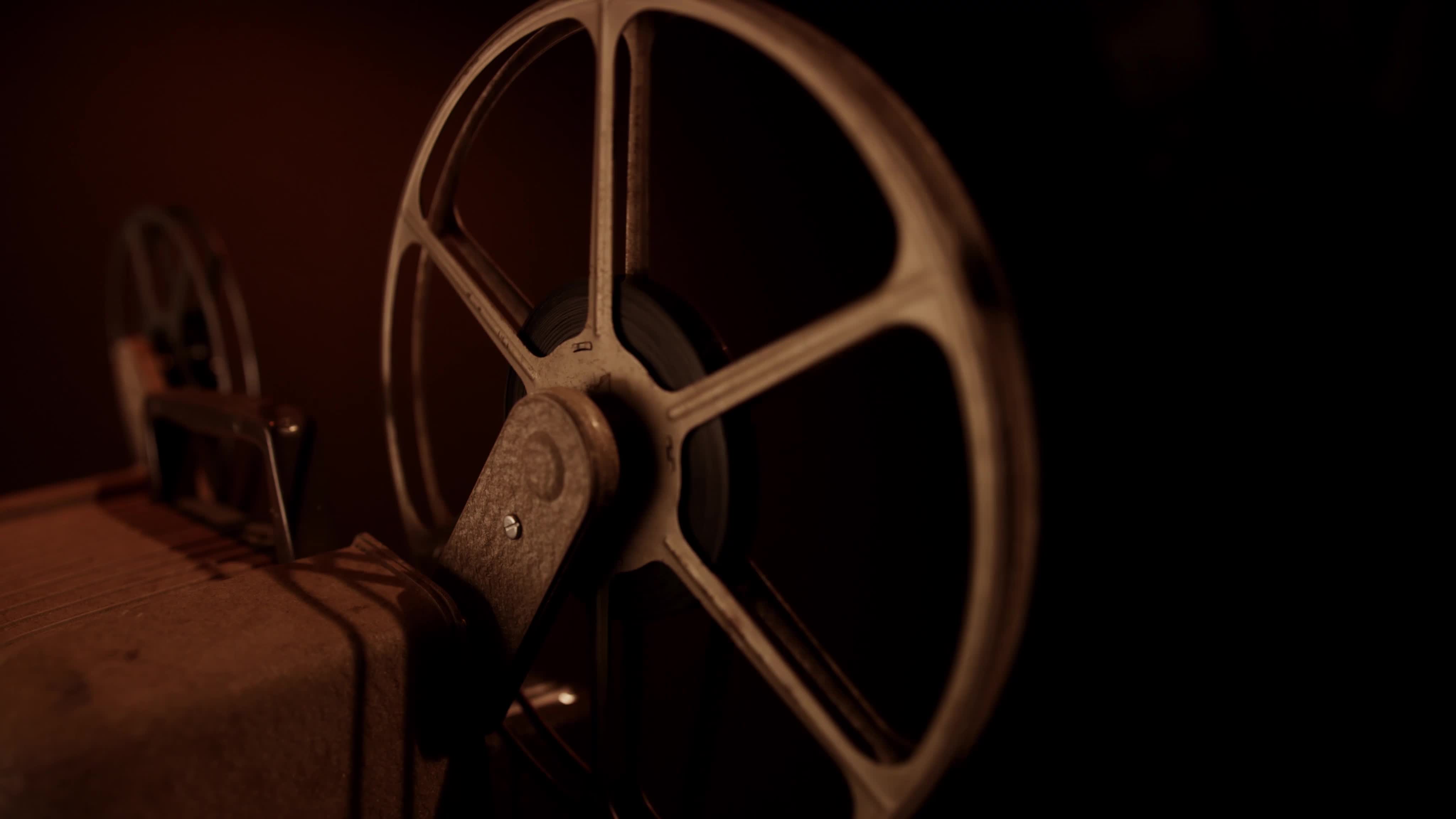 Traveling shot of rusty film reels spinning with dark illumination