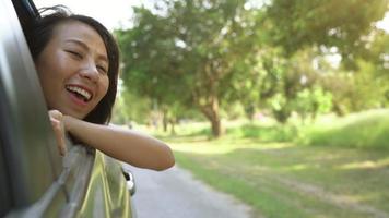 Young asian woman enjoying feeling wind through car window. video