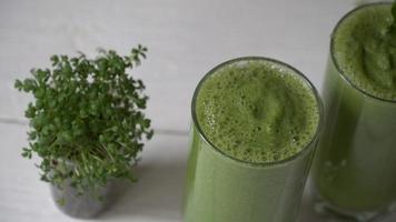 Blended green smoothie with ingredients or cocktail on white background. video