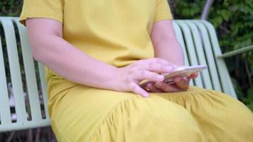 mujer usando un teléfono inteligente en un columpio al aire libre.
