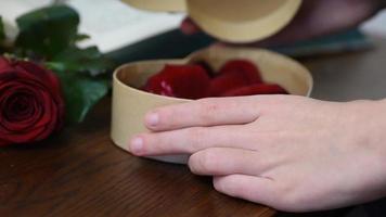 Valentine Gift. Young Girl opening heart gift box with rose petals video