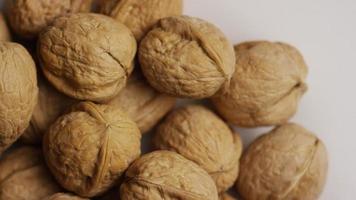 Cinematic, rotating shot of walnuts in their shells on a white surface - WALNUTS 054 video