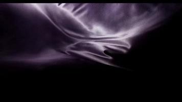 Dark purple fabric moved by the wind with formless waves from lower left and right corner in 4K video