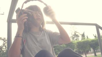 Beautiful young asian woman listening to music on a smart phone in the city. Young asian woman relaxing listening to music on the street. video