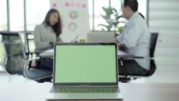 portátil con pantalla verde sobre una mesa en la oficina