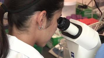 científico femenino en microscopio video