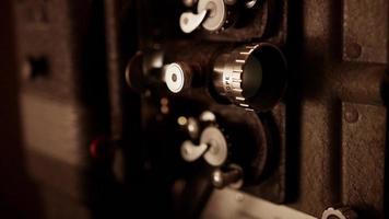 Short vertical panning shot of film projector showing the sprocket mechanism, lens and lamp flashing in 4K video