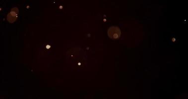vita små partiklar och stora suddiga bokehpartiklar som rör sig raqndomly på mörk bakgrund i 4k video