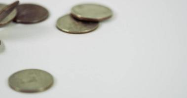 en massa mynt av kvart dollar faller över två mynt på vitt bord, fem mynt placeras i scenen i 4k video