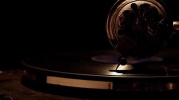  Dark extreme close up of decorated needle playing a vinyl disc on classic record player and weak overhead lighting in 4K video