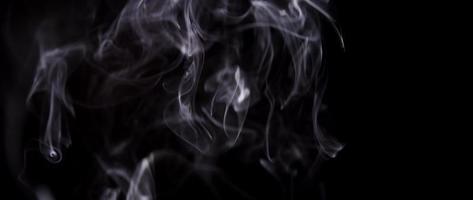 White smoke drawing thin shapeless lines in darkness in 4K video