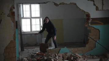 Hombre deprimido y loco lanza una silla a través de una habitación en una vieja casa abandonada