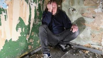 Depressed and angry man is sitting in the corner in an abandoned house video