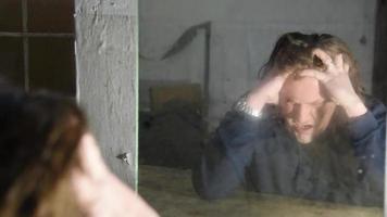 homem deprimido e zangado está sentado em frente a seu reflexo em uma velha casa abandonada video