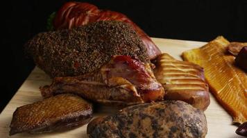 Rotating shot of a variety of delicious, premium smoked meats on a wooden cutting board - FOOD 082 video