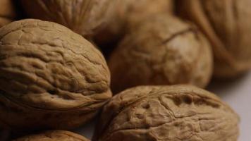 Cinematic, rotating shot of walnuts in their shells on a white surface - WALNUTS 076 video