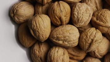 Cinematic, rotating shot of walnuts in their shells on a white surface - WALNUTS 051