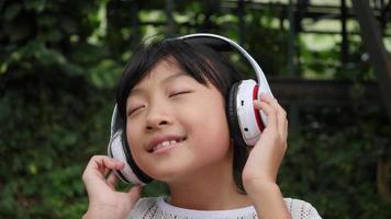 Little girl listens to music from headphone and good feeling video