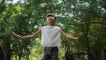 menina asiática brincando ao ar livre em câmera lenta, girando, sorrindo e levantando as mãos no ar video