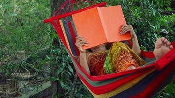 mujer joven, acostado, en, hamaca, y, leer un libro