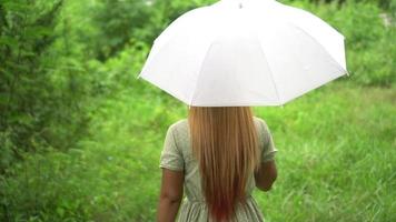 Woman walking hand holding white umbrella at the park  video