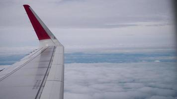 Wing of an airplane flying above the clouds from window plane view video