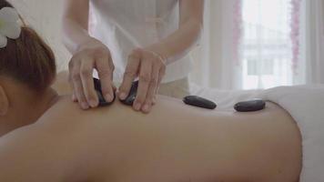 Mujer joven con masaje con piedras calientes en el spa
