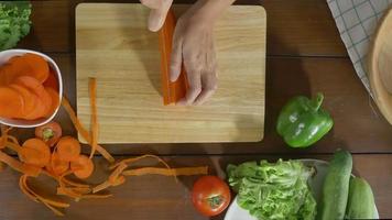 Draufsicht des Frauenchefs, der gesundes Essen des Salats macht und Karotte auf Schneidebrett in der Küche hackt. video