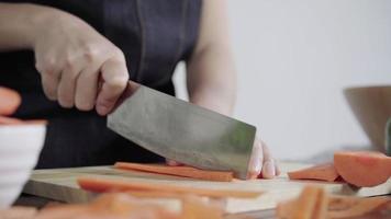 Nahaufnahme der Hauptfrau, die Salat gesundes Essen macht und Karotte auf Schneidebrett in der Küche hackt. video