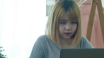 Beautiful young smiling Asian woman coming on laptop while at home in office com space. video