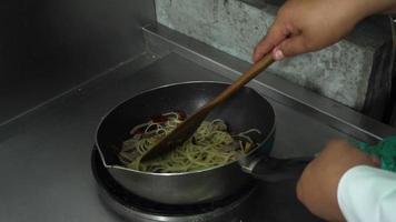 ralenti - les chefs préparent et font cuire des spaghettis dans la cuisine d'un restaurant.
