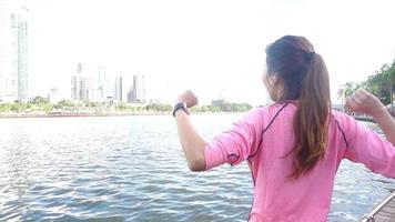 slow motion - Aziatische mooie vrouw in fitness outfits gebruikt een smartwatch om naar muziek te luisteren, te praten aan de telefoon na het hardlopen in het park. aantrekkelijke gezonde vrouwelijke joggen.