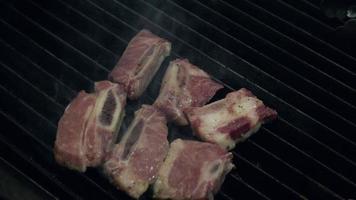 chef-kok zet ongekookt vlees stuk op hete rookvrije grill met vuur eronder met behulp van een metalen tang, close-up slow motion. video