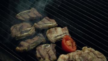 matlagning chef sätter okokt kött bit på het rökning grill med eld under med metallpincett, närbild slow motion. video