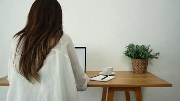 vacker ung le kvinna som kommer på bärbar dator medan du njuter av att dricka varmt kaffesammanträde i ett vardagsrum hemma. video