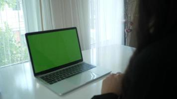 Nahaufnahme der Hände einer Frau, die auf einem Laptop mit grünem Bildschirmplatzhalter kommen