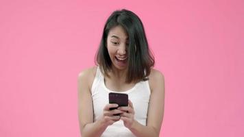 jovem mulher asiática usando smartphone, verificando as mídias sociais, sentindo-se feliz, sorrindo em roupas casuais. video