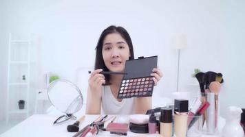 Happy beautiful young Asian woman use cosmetics review make up tutorial broadcast live video to social netcom.