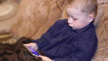 niño jugando con el teléfono móvil en el sofá video