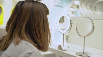 junge asiatische Frau, die sich in den Spiegel innerhalb eines Geschäfts schaut video