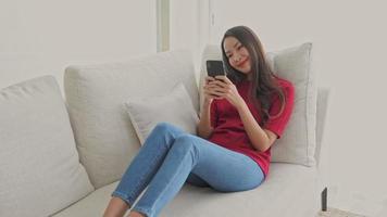 Woman using mobile phone on sofa video