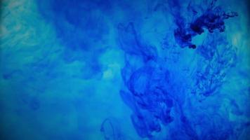 Blue color paint ink pouring over the glass with inky drops falling and abstract smoke explosion. video