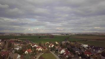 Drone flies over a village towards trees in 4K video