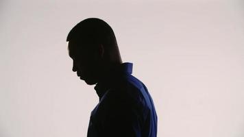 silhouet van een jonge zwarte man die mediteert en zijn hoofd naar beneden kantelt en zich vervolgens naar de camera wendt video
