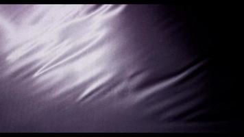donkerpaarse stof bewogen door de wind met grote golven vanuit de rechterbovenhoek in 4k video